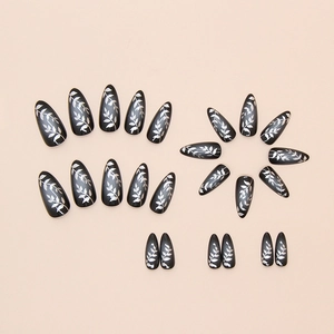 Black and silver almond press-on nails featuring elegant leaf patterns on pink background