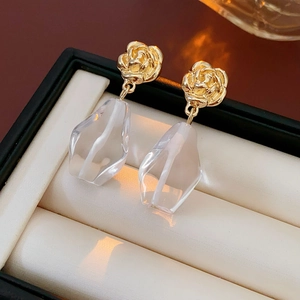 Detail of golden rose flower earrings with transparent water drop charms in a jewelry box