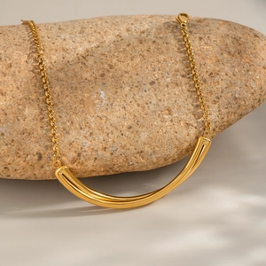 Minimalist 18K gold titanium steel curved tube necklace on natural stone display
