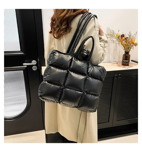 Vista dettagliata della borsa tote trapuntata nera sulla spalla con elegante trench beige