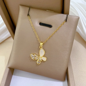 Close-up of gold butterfly pendant featuring white shell inlay and sparkling crystals