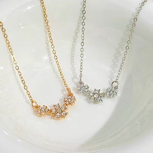 Dettaglio di collane in oro rosa e argento con ciondoli a fiore in cristallo