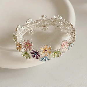 Macro shot of colorful daisy enamel stretch bracelets on a minimalist ceramic tray