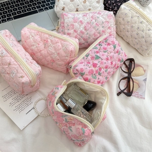 Flat lay of floral quilted cosmetic bags with bunny patterns and office accessories