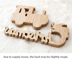 Detail of wooden Christmas train ornament with laser-cut letters on soft snow background