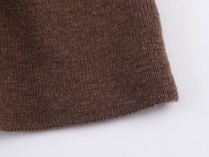 Close-up of dark brown ribbed knit texture on a women top with layered decoration