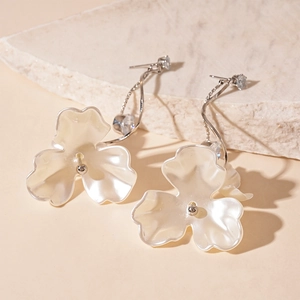 Detail of floral drop earrings with white pearl-like petals and zircon inlay