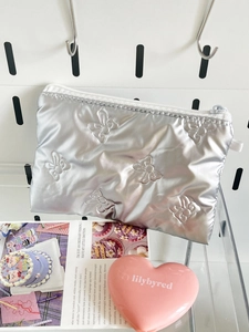 Close-up of silver quilted bow pattern on a metallic texture mini storage pouch