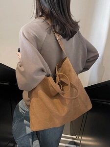 Brown minimalist large capacity tote bag with adjustable strap worn by model