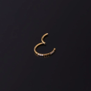 Golden stainless steel nose ring with sparkling cubic zirconia on black background
