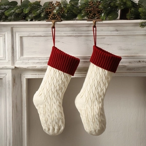 Classic cable knit Christmas stocking with red cuff hung on mantel with holiday decor