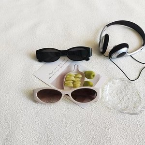 Flat lay of retro oval cat-eye sunglasses in black and beige on white textured fabric