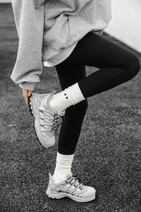 Detailed side view of grey outdoor athletic shoes featuring BOA lacing and white ribbed socks