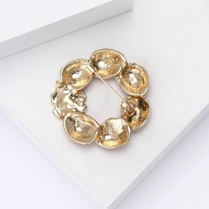 Macro view of a round golden brooch featuring rustic handmade metal textures