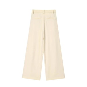 Détail d'un pantalon large jaune crème montrant les plis à la taille et la poche arrière