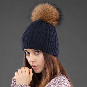 Detailed knit texture of navy blue beanie featuring a large brown faux fur pompom