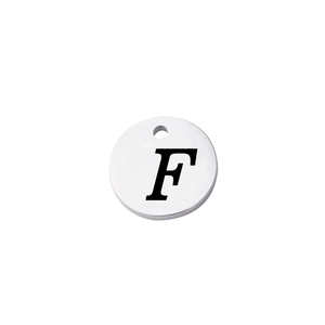 Macro shot of a mirror-polished round stainless steel charm with engraved letter F