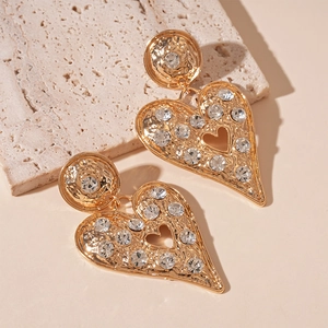 Detail of gold heart earrings featuring vintage hammered texture and sparkling crystals
