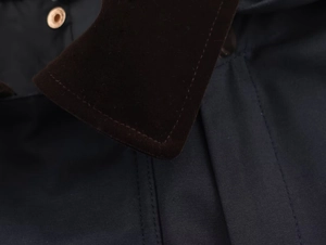 Close-up of contrast corduroy collar and gold metal button on hooded windbreaker coat