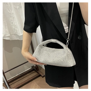 Detail of silver rhinestone evening bag with chain strap held by model in black suit