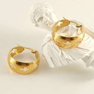 Gold stainless steel hoop earrings with hollow cross patterns on white plaster bust