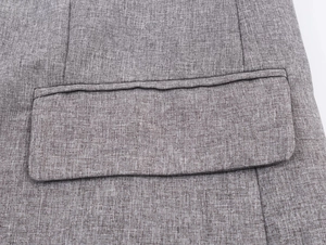 Close-up of herringbone blazer showing textured grey fabric and detailed pocket flap stitching