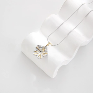 Close-up of a two-tone flower pendant necklace on white artistic stone stand