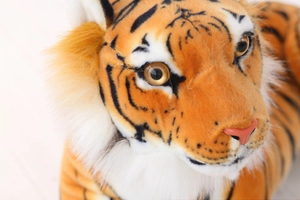 Close-up of realistic plush tiger head featuring detailed faux fur texture and lifelike eyes