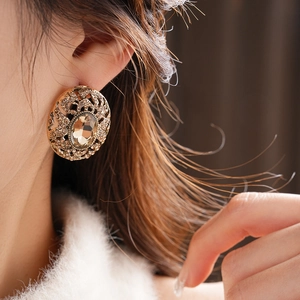 Close-up of vintage oval hollow earrings with amber crystals and sparkling rhinestones