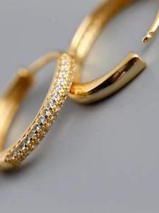 Macro shot of polished gold earring featuring micro-pave cubic zirconia setting detail