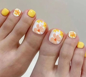 Detail of yellow and white toe nail patches with orange floral designs for pedicure