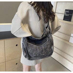 Vue arrière d'un mannequin portant un grand sac bandoulière en denim noir délavé