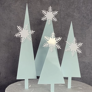 Detail shot of light blue acrylic Christmas tree cake topper with white snowflake accents