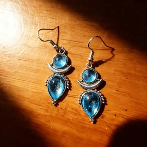 Detail of silver drop earrings featuring deep blue moonstone resin in a vintage style