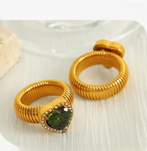 Detail of heart-shaped green crystal ring with pavé stones and ribbed gold band texture