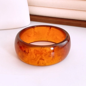 Macro shot of wide amber resin bangle showing detailed smoky textures and smooth finish