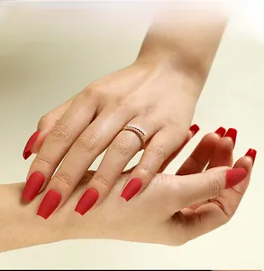 Matte red coffin press-on nails with golden pearl ring on light beige background