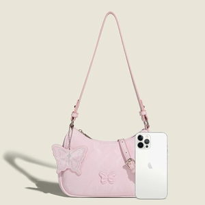 Pink butterfly relief shoulder bag with matching charm and adjustable strap shown next to phone