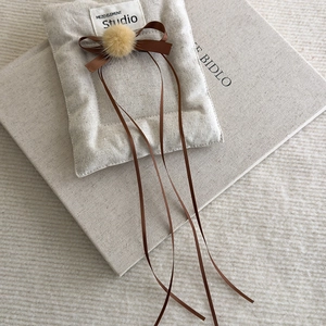 Close-up of ballet style hair clip with soft plush ball and satin brown ribbons