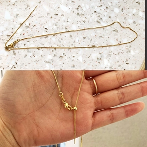 Detail of adjustable gold-plated box chain necklace with a smooth sliding clasp design