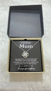 Silver heart knot necklace in a black gift box with an English greeting card for Mom