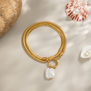 Détail d'un bracelet double chaîne serpent dorée avec perle baroque irrégulière