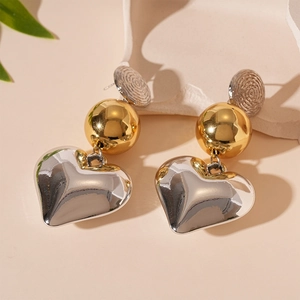 Detail of mixed-metal geometric heart earrings with silver studs and golden spheres
