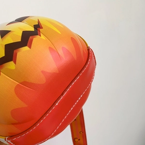 Detailed close-up of orange pumpkin shoulder bag with black zigzag mouth and stitching