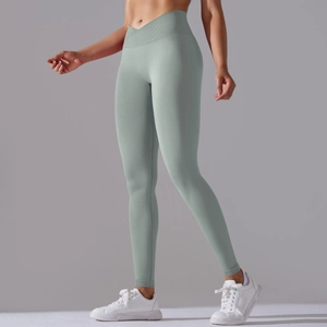 Detail view of the high-waisted V-shaped crossover waistband on green yoga leggings