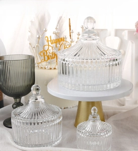 Detailed view of three glass storage jars with embossed vertical stripes and lids