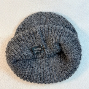 Macro detail of the care label inside the dark grey wool blend knitted beanie hat