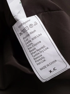 Detail view of clothing care label showing 100% polyester fabric and washing instructions