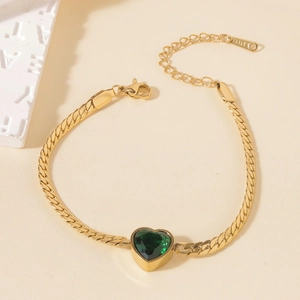 Detail of gold curb chain bracelet with heart-shaped green stone and S.STEEL stamp