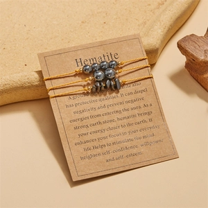 Detail of three braided hematite bracelets with spherical beads on craft card packaging